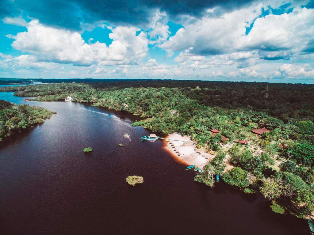 Vista aérea del Amazon EcoPark Jungle Lodge mostrando su playa privada en el río y la densa selva amazónica.