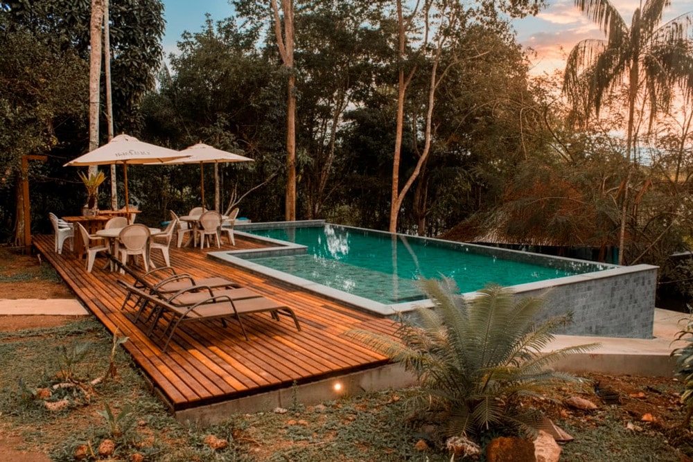 Piscina infinita y zona de relax del Amazonia Jungle Hotel con vistas a la selva tropical de Brasil al atardecer.