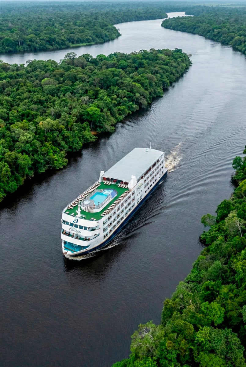 Crucero de lujo Iberostar Heritage Grand Amazon navegando por el río Amazonas rodeado de selva virgen, con piscina en la cubierta superior.