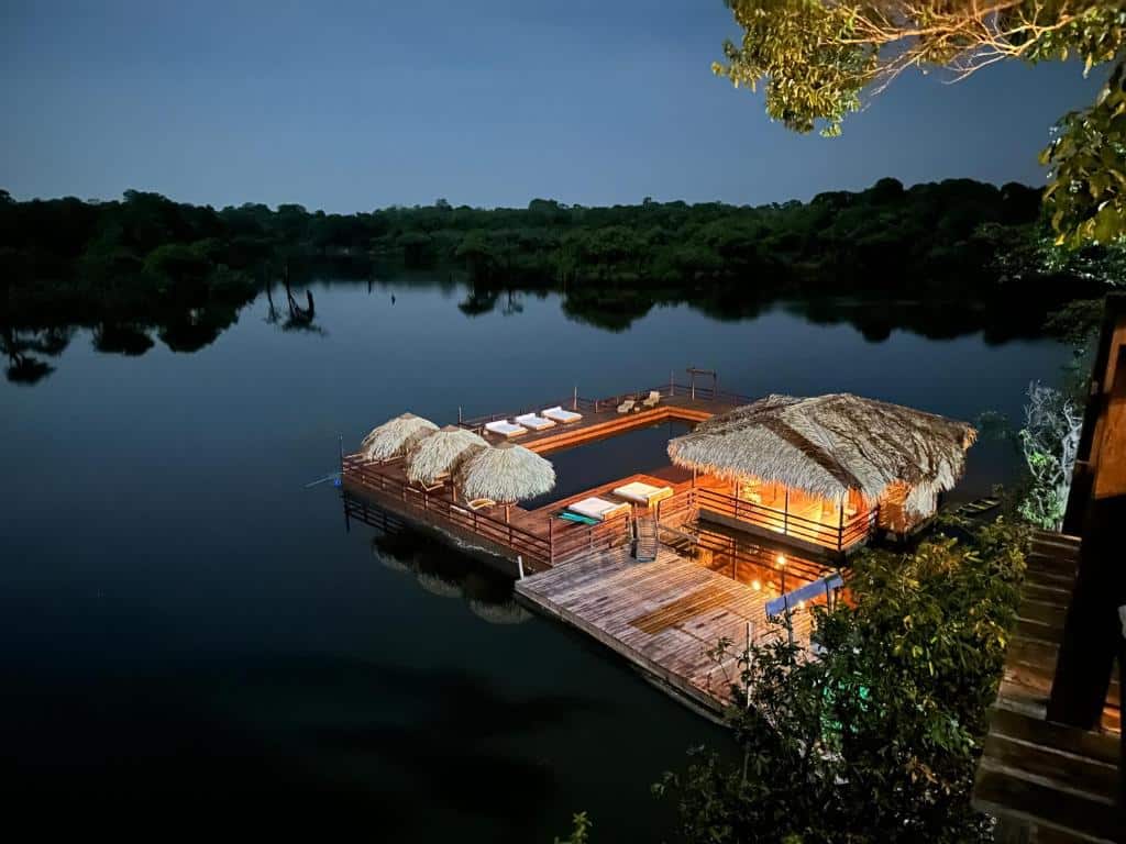 Piscina flotante iluminada de noche en el Juma Amazon Lodge, un hotel de selva exclusivo en el corazón del Amazonas, Brasil.