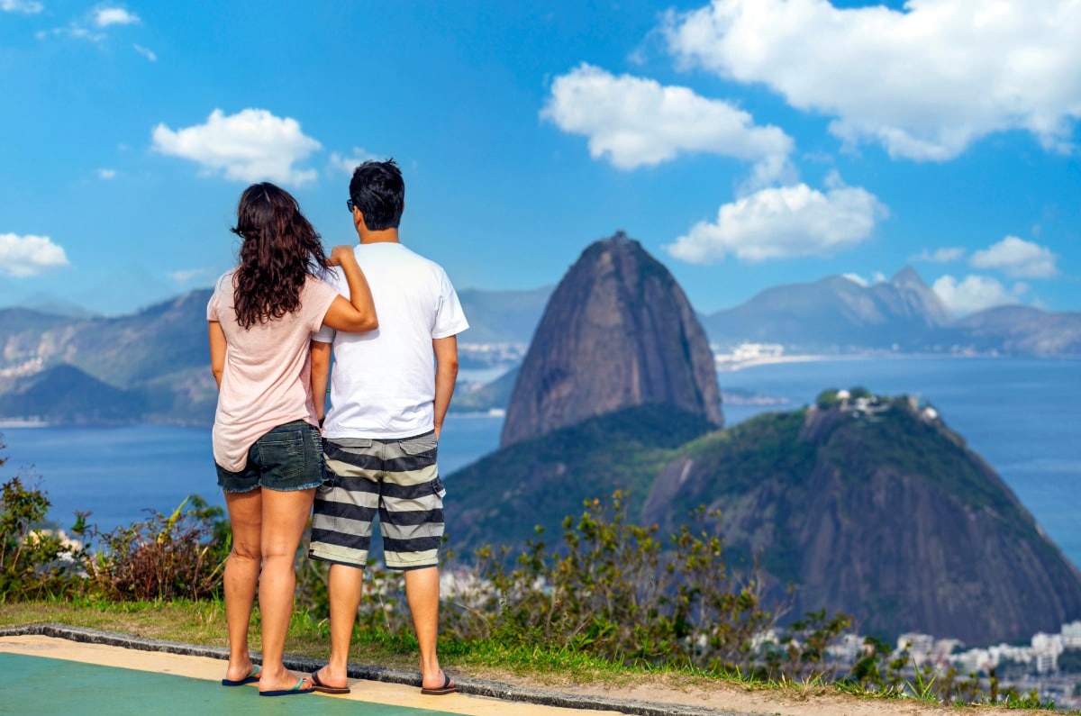 Pareja abrazada en un mirador panorámico contemplando el Pan de Azúcar y la bahía durante su luna de miel en Río de Janeiro, Brasil.