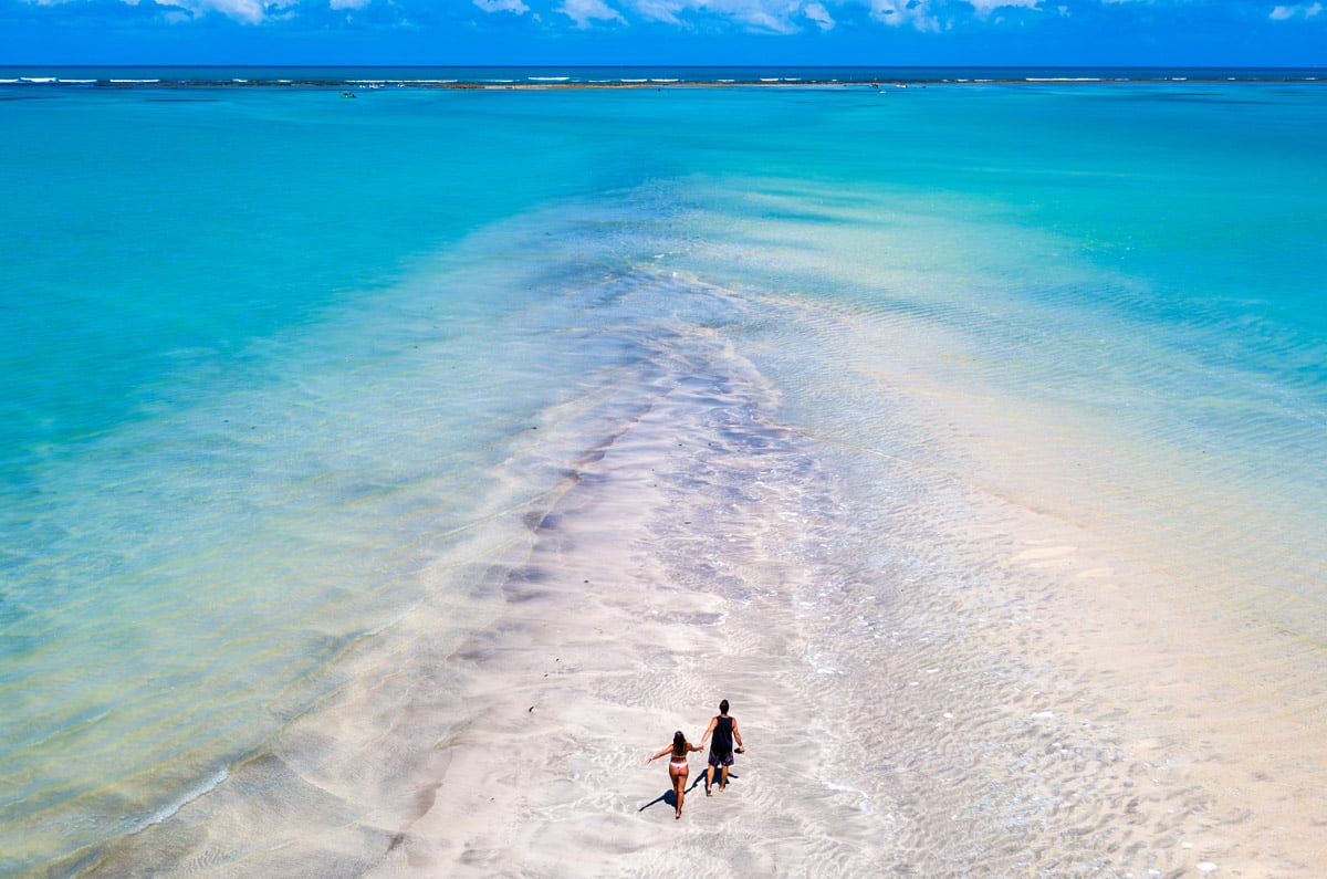 Pareja caminando por el "Camino de Moisés" en las piscinas naturales de Maragogi, Alagoas.