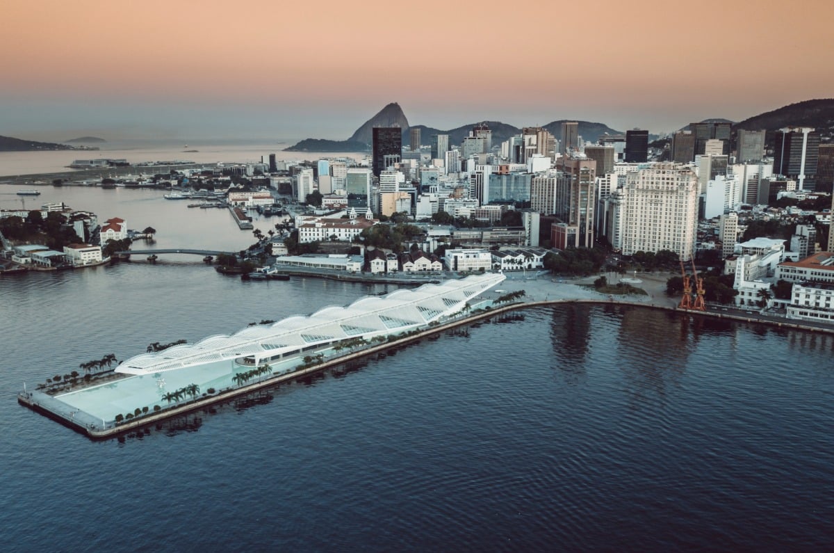 Vista aérea del Museo del Mañana y la zona portuaria de Río de Janeiro al atardecer, con la arquitectura futurista de Santiago Calatrava y el Pan de Azúcar al fondo.