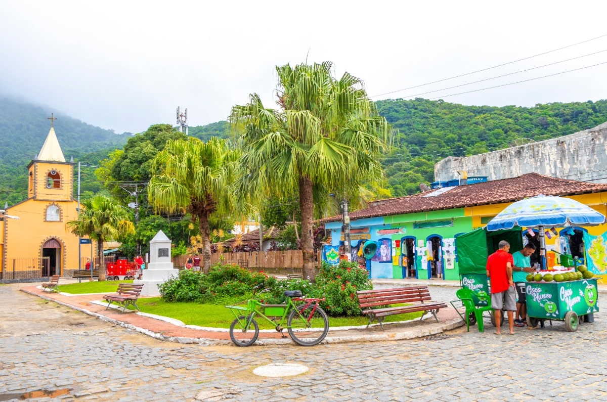 Plaza principal de Vila do Abraão con su iglesia histórica, palmeras y puestos callejeros en Ilha Grande.