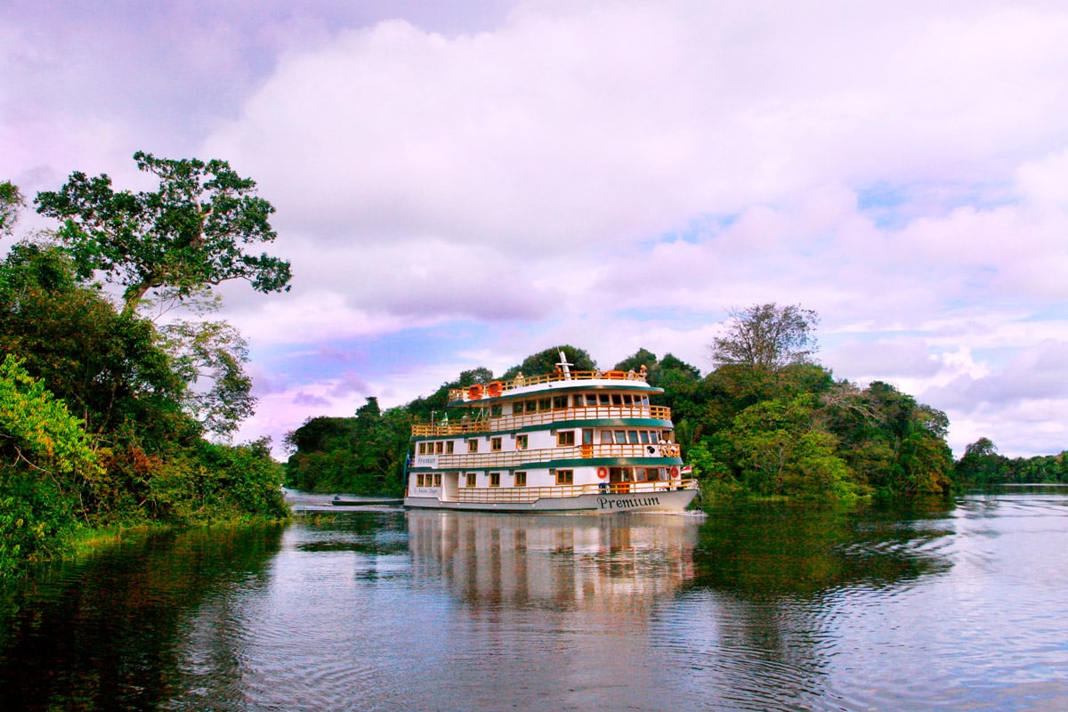 Crucero boutique Amazon Clipper Premium navegando por un canal estrecho de la selva amazónica en Brasil.