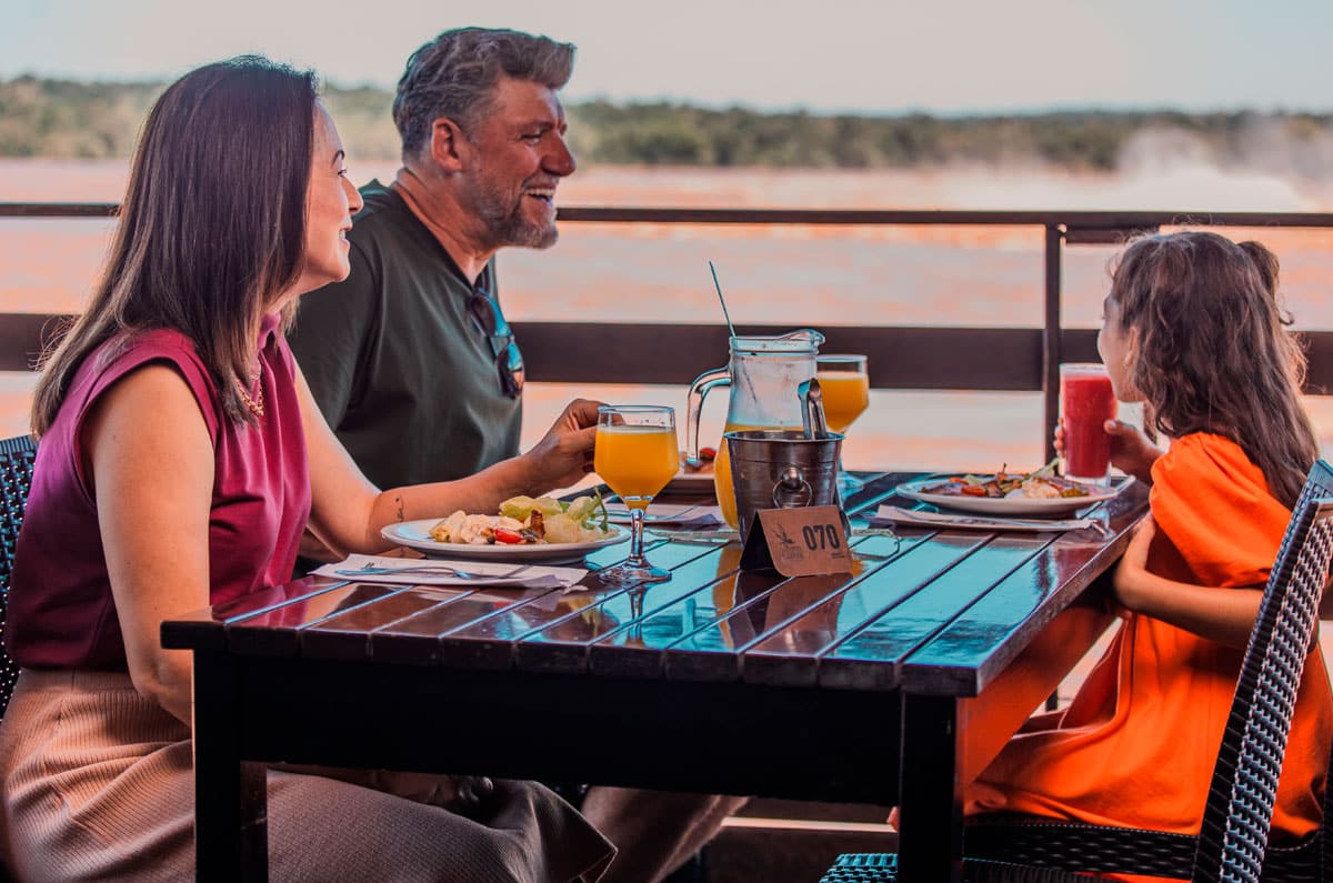 Familia almorzando en el restaurante Porto Canoas con vistas panorámicas a las Cataratas de Iguazú.