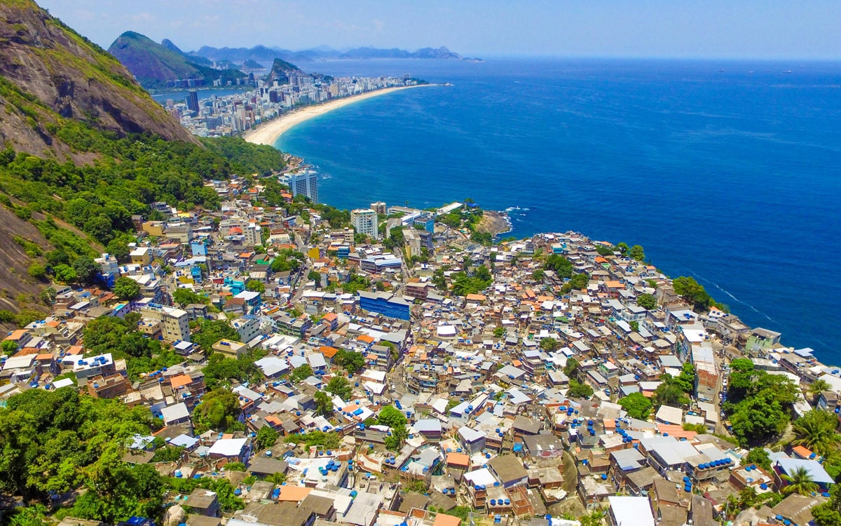 Vista aérea de una favela en Río de Janeiro con el mar y la playa de Copacabana al fondo.