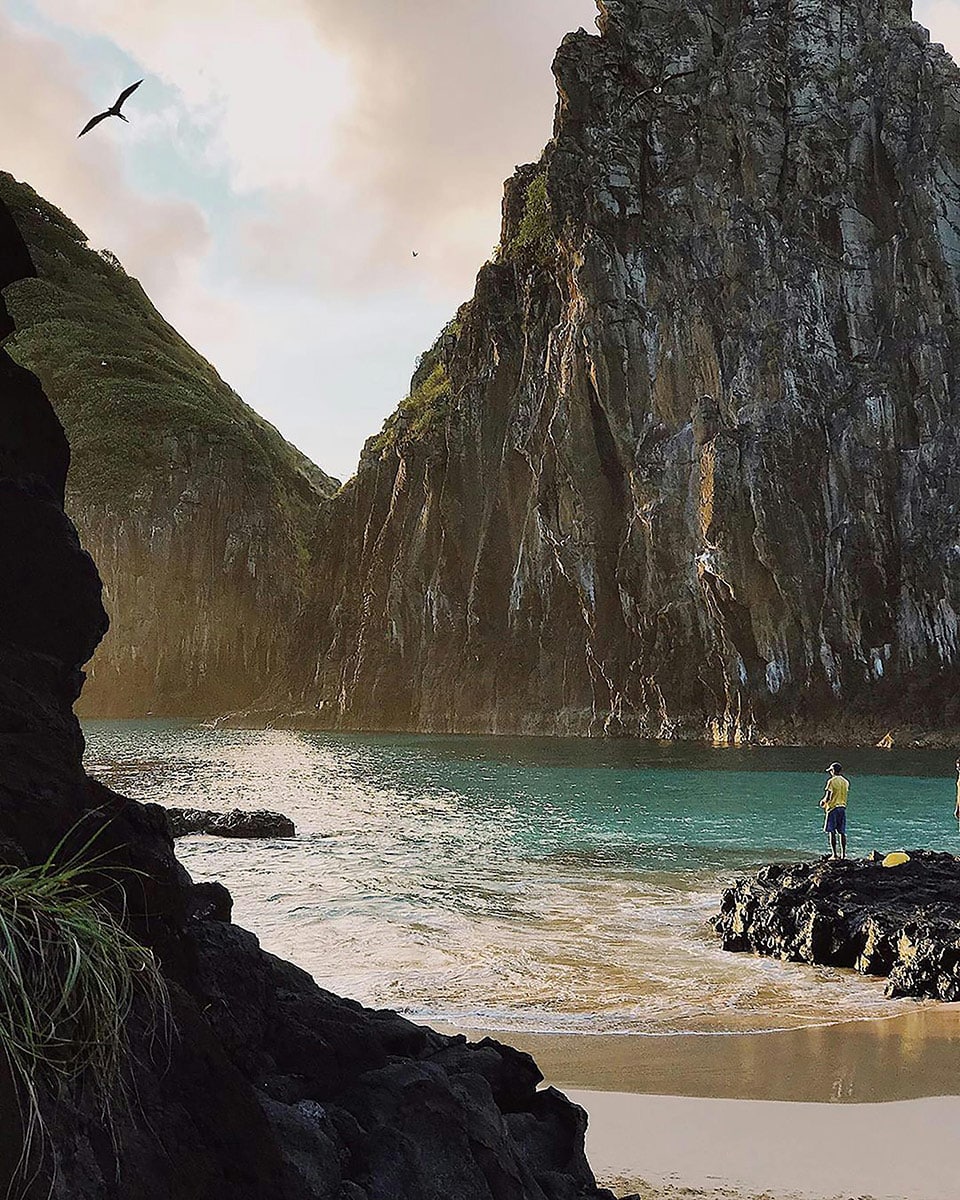 Paisaje virgen de Fernando de Noronha, Brasil, mostrando acantilados volcánicos y aguas turquesas cristalinas, ideal para viajes exclusivos y lunas de miel de lujo.