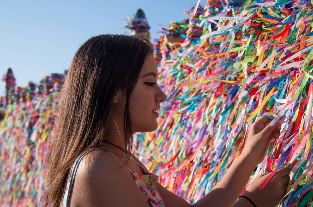 Viajera atando una cinta tradicional de los deseos en la Iglesia de Nosso Senhor do Bonfim durante una luna de miel en Salvador de Bahía, Brasil.