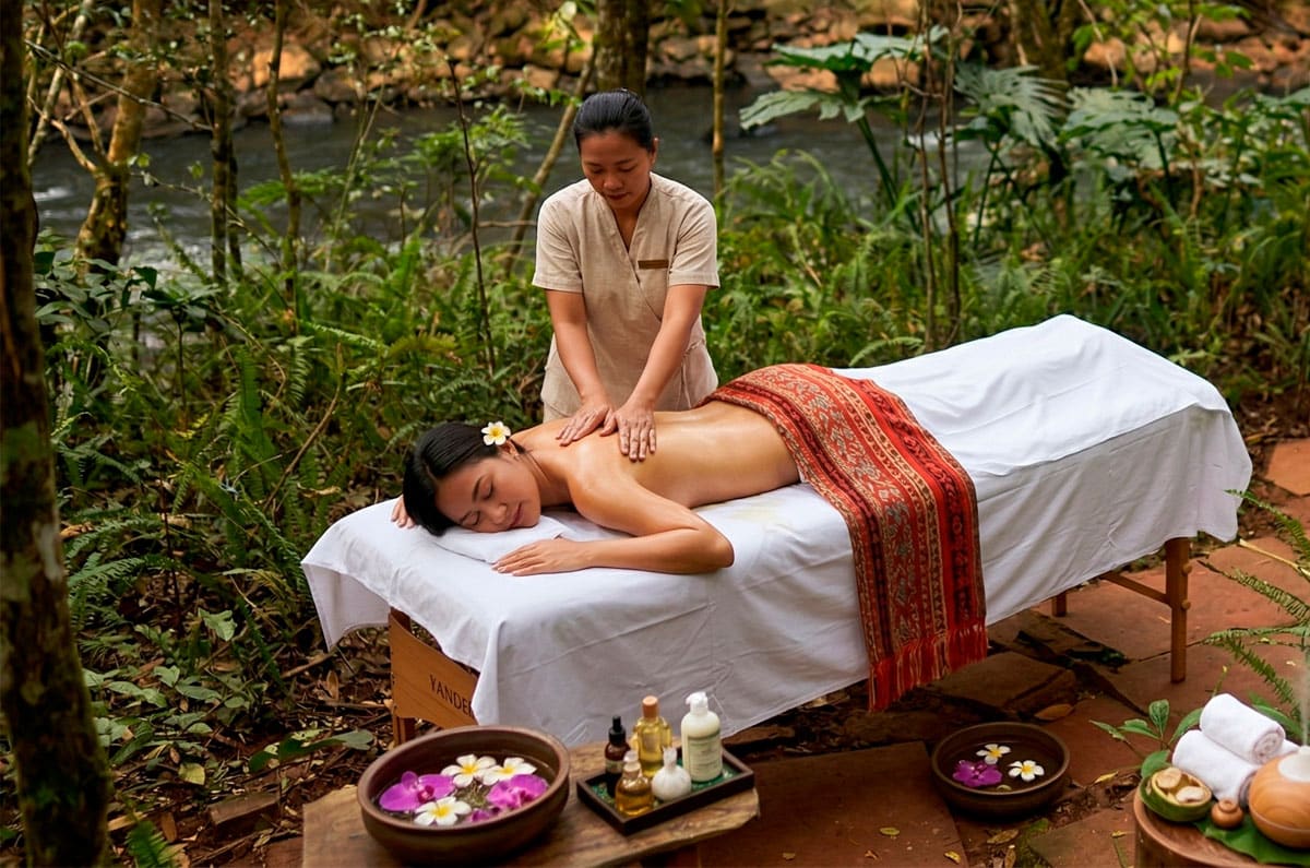 Mujer recibiendo un masaje relajante en un spa al aire libre en mitad de la selva de Iguazú, Brasil, con el río de fondo.
