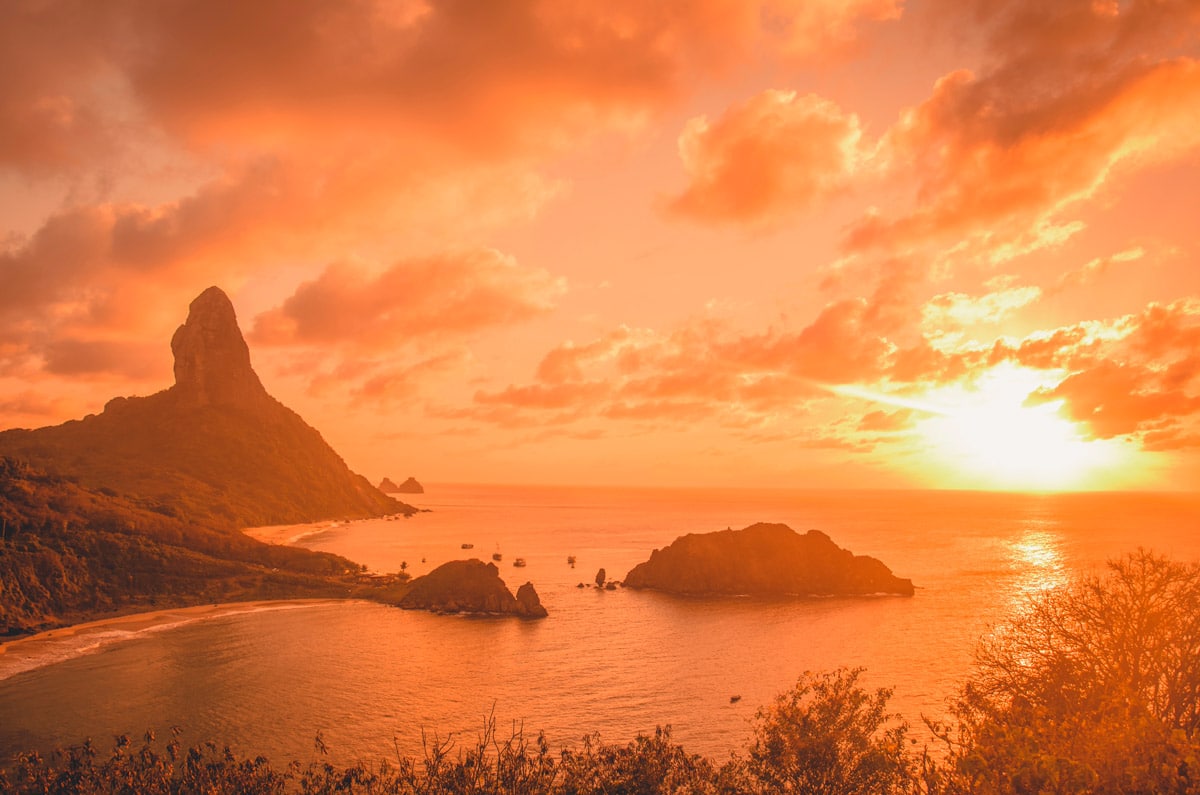 Atardecer dorado sobre la bahía de Fernando de Noronha, mostrando la belleza virgen del archipiélago protegido.