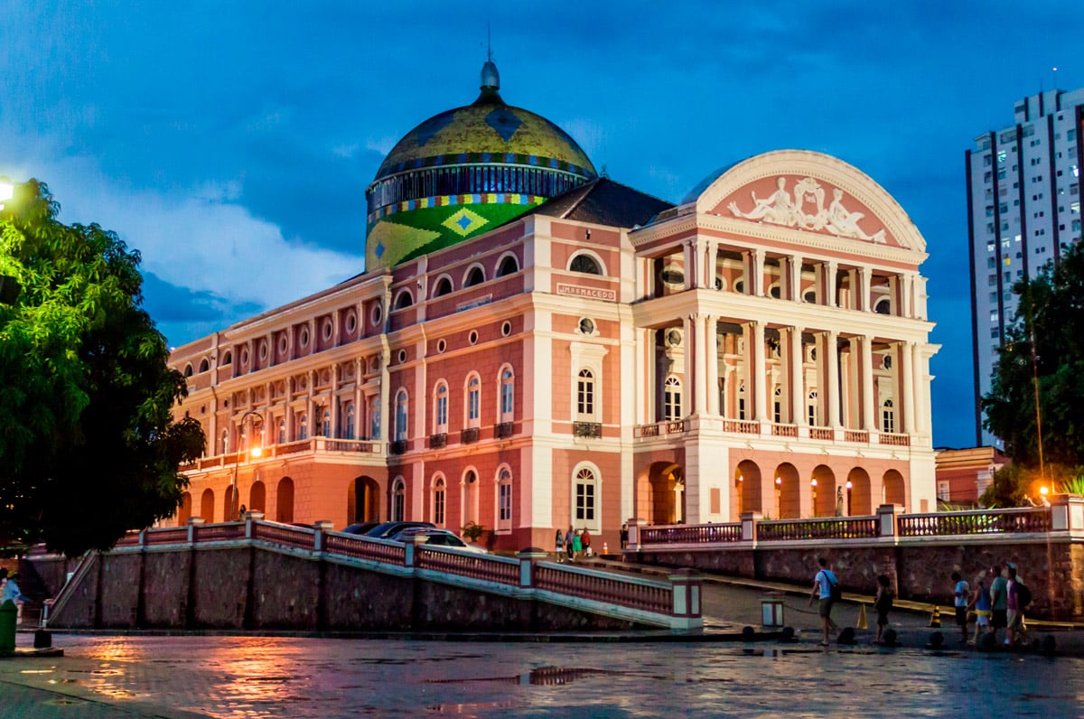 Fachada iluminada del Teatro Amazonas en Manaos al atardecer, símbolo del lujo arquitectónico de la época del caucho en el corazón de la selva brasileña.