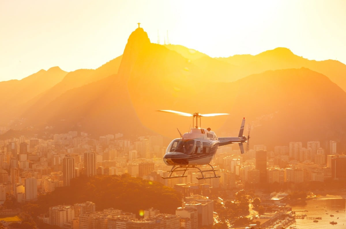 Vistas aéreas exclusivas de Río de Janeiro desde un helicóptero privado al atardecer, con la silueta del Cristo Redentor y el Corcovado de fondo.