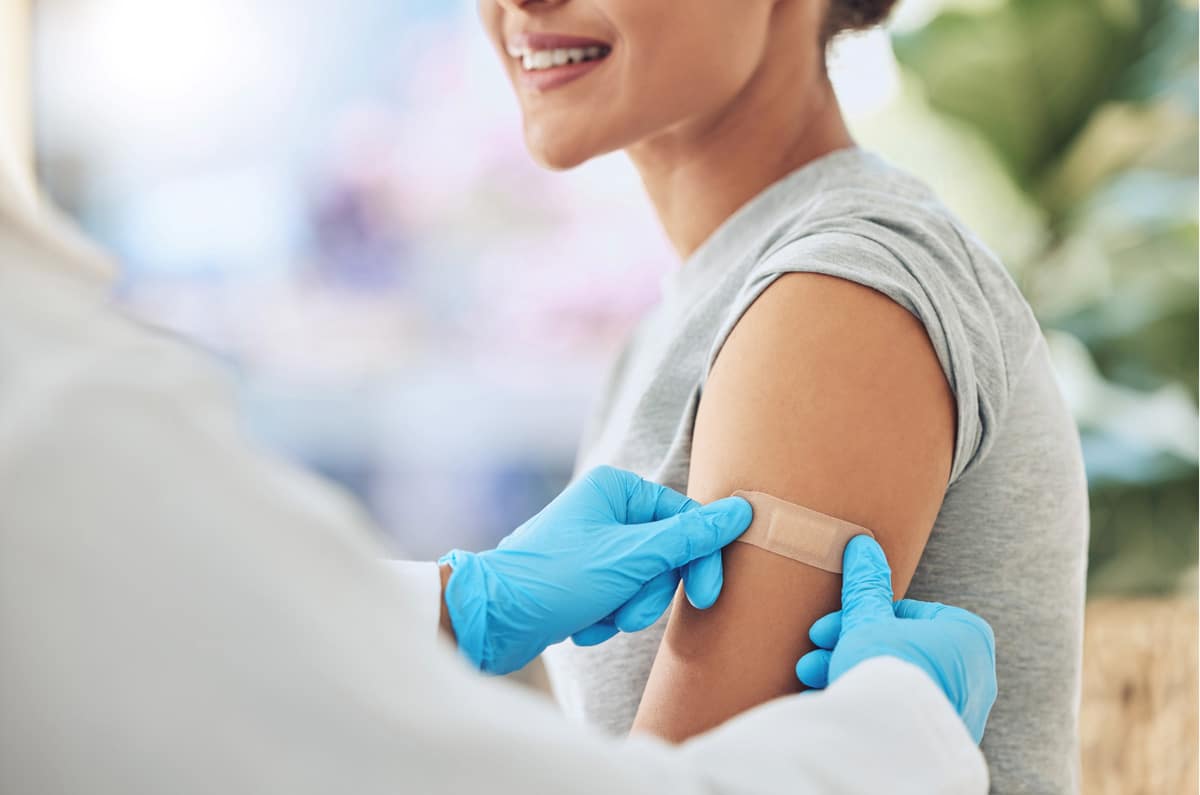 Personal sanitario colocando un apósito en el brazo de una paciente tras una vacunación.